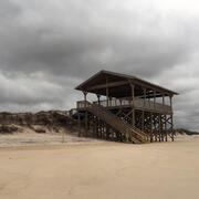 A pavilion or lookout deck that was previously on a dune, now with exposed support pilings after a series of storms