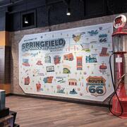 A large illustrated wall cartoon-style map and red vintage Phillips 66 gas pump against a wall