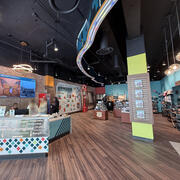 Wide view inside the visitor center, showing seating, merchandise displays, and a wall reading “Visit Springfield Missouri."