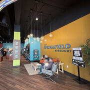 Wide view inside the visitor center, showing seating, merchandise displays, and a wall reading “Visit Springfield Missouri.” 