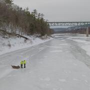 Two men standing next to an Ice Sled on the frozen Delaware River as they prepare to make a measurement