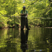 USGS scientist standing in a river collecting a water sample