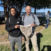 Two people smiling for photo outside holding decomposed clothing