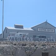 Photo of the Tonopah Historic Mining Park Visitor Center; gray building against bright blue sky.