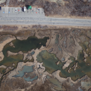Birds eye view of green pools surrounded by low lying tan marsh vegitation