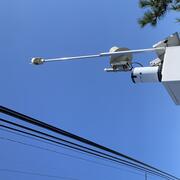 A white square sensor box with solar panel, rain gage, and antenna on the side of a bridge overlooking the water