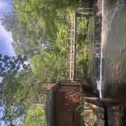 Looking upstream at a footbridge over a river next to a brock house