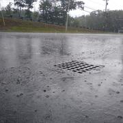 A stormdrain in a parking lot during a rainstorm.