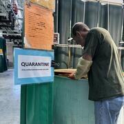 Scientist, Paul Hershberger, leans over a green tank of fish in the Seattle wet lab