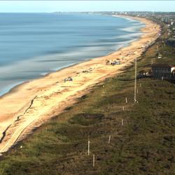 Distant view of sandy yellow beach stretching from bottom left to upper right of photo.