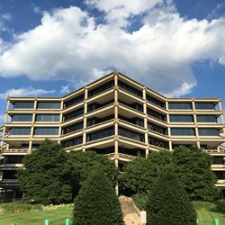 Image shows an office building with blue sky and clouds overhead