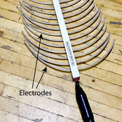A long wand with numerous, plastic-coasted, half-moon-shaped wires sticking out.