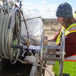 USGS hydrologists collects a groundwater sample pumped through a hose into a bottle