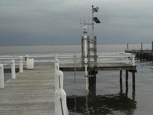 Looking along a wooden pier into the bay at USGS tide sensor station