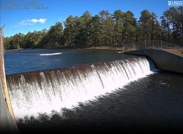 Looking out on water falling over a dam at the outlet of a lake