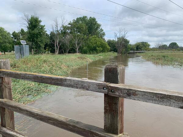 Streamgage on a grassy shoreline next to a flooded river