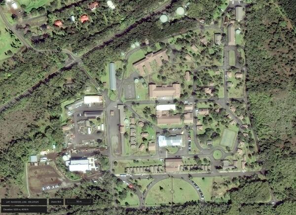 Satellite image of buildings and roads surrounded by grass and vegetation
