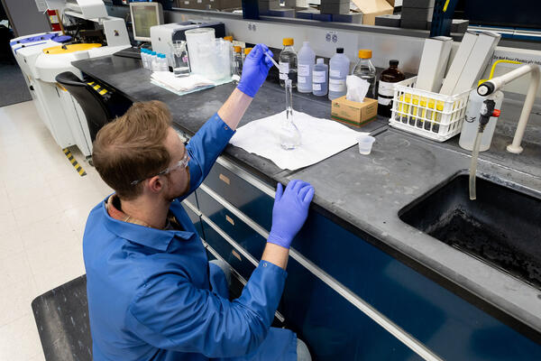 scientist using pipette to fill a flask