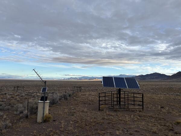 Groundwater monitoring station in desert at dusk with silhouetted mountains in the background.
