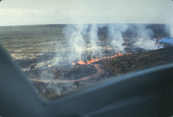 Color photograph of a line of erupting vents and a channelized lava flow
