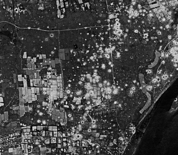 A satellite image with black background and white rectangles and round splotches.