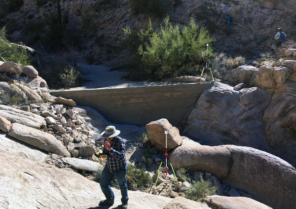 A person walks near a remote sensing station at a water catchment in Cabeza Prieta National Wildlife Refuge