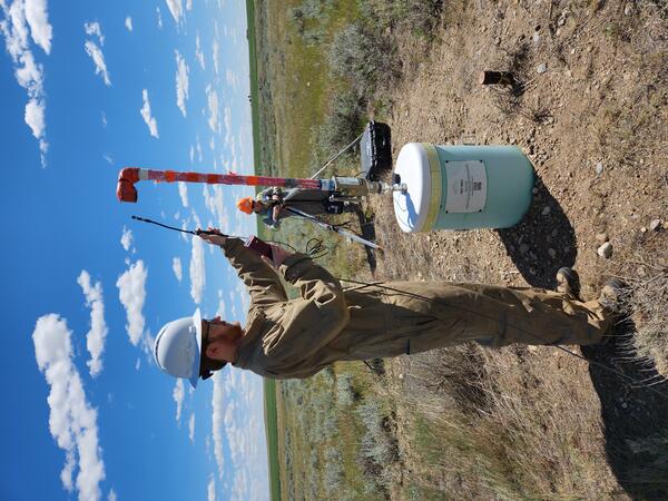 USGS scientist standing taking a methane reading from an orphan well in Montana