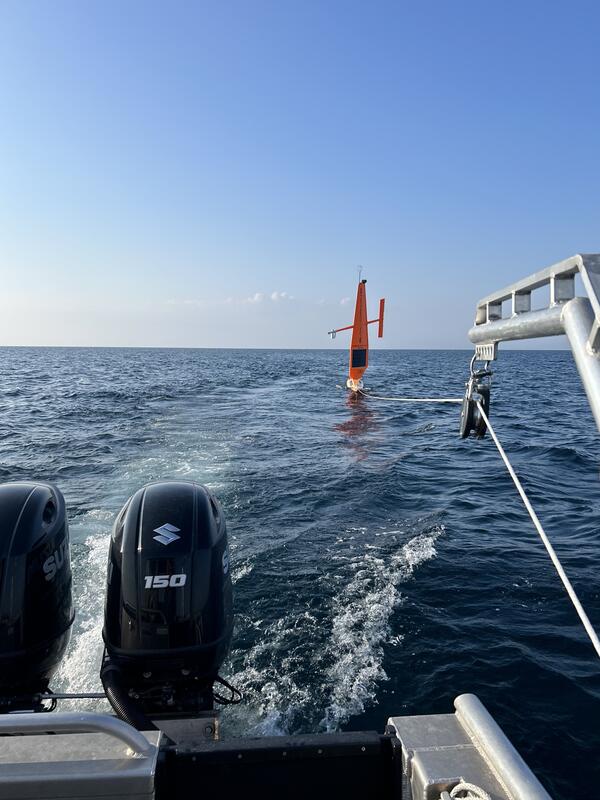 A Saildrone being towed behind a small research vessel in Lake Huron