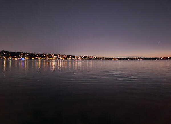 skyline at night with lots of artificial light from houses and buildings along the lake