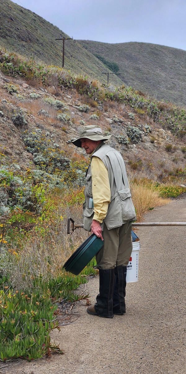 Scientist Charles Drost carries gear while walking along a road on San Clemente Island during a monitoring study