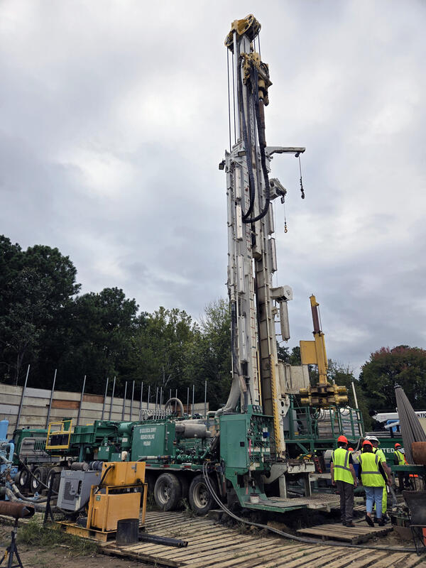 A drilling rig at the site of the James River Extensometer. Several individuals in hardhats and safety vests tour the rig.