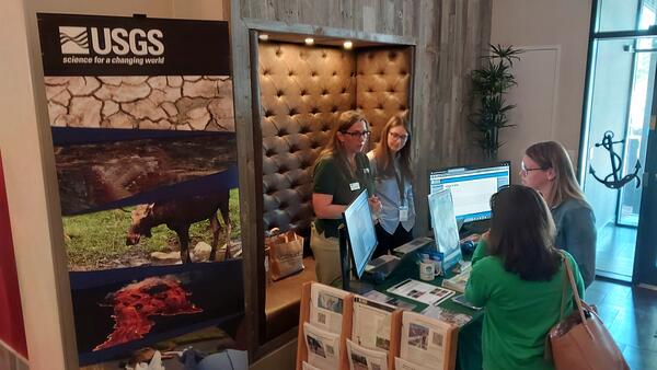 Two USGS scientists behind a booth talking to two people on the other side of the booth