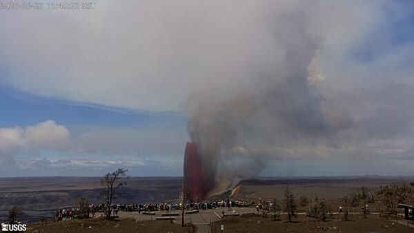 Color photograph of lava fountain erupting with visitors viewing in the foreground