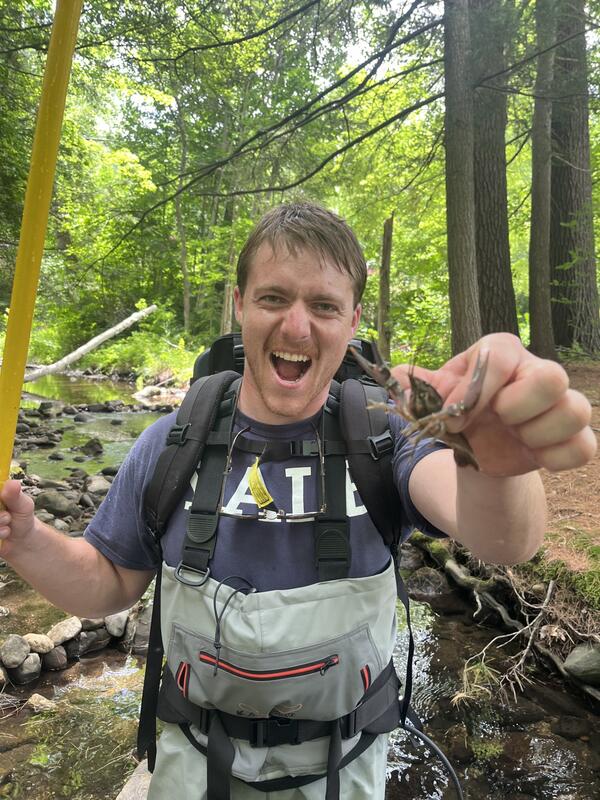 Man in waders holding a crayfish in the foreset