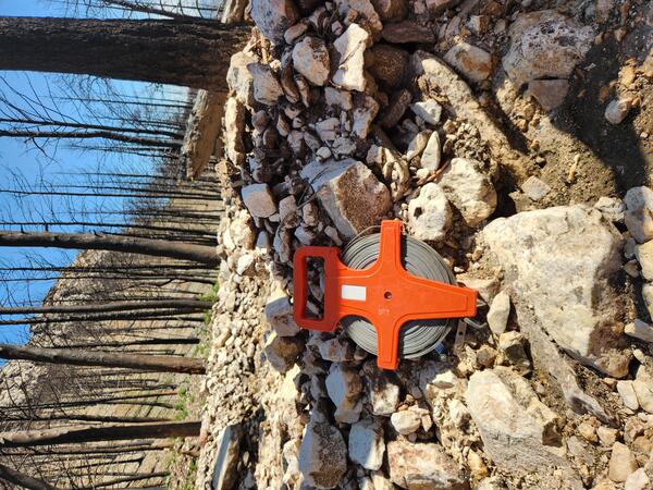 tape measure sit on top of a deposit of rocks and mud