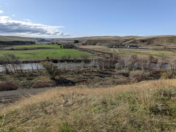 View from a high point looking down at the valley. leafless trees line the near bank on a blue sky day.