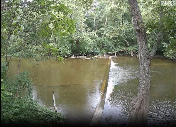 Looking across a river along the concrete weir 