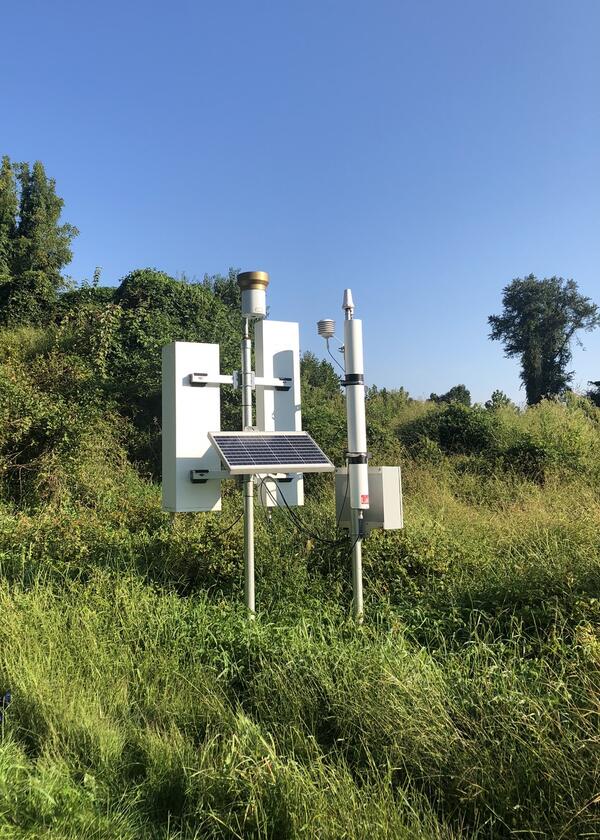 CRNS monitoring station on a grassy hillside with open blue sky overhead.