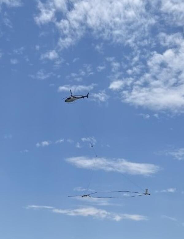 Photo of helicopter towing large sensor that looks like hula hoop.