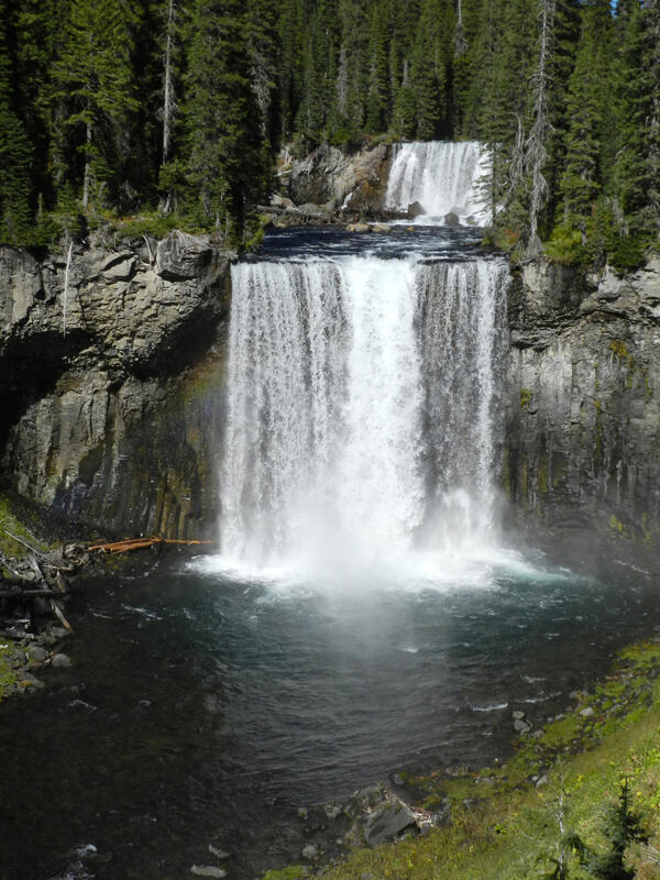 Two-tiered waterfall with wide falls plunging into a dark river