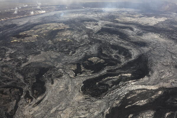 Black and light gray lava flows cover a volcanic crater floor