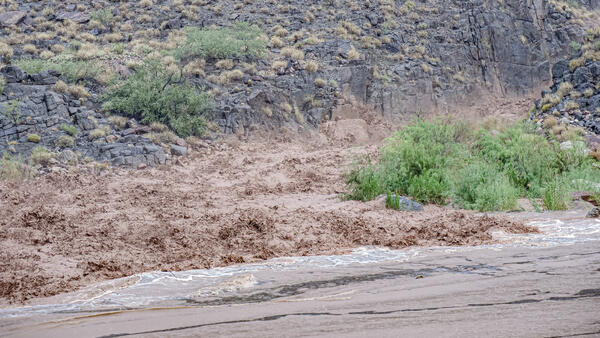Muddy floodwaters rush down a canyon into the Colorado River, Grand Canyon, during a flash flood event