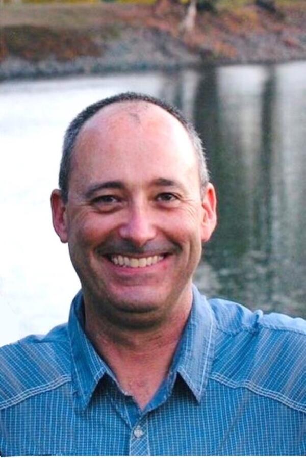 headshot of a man with a river in the background