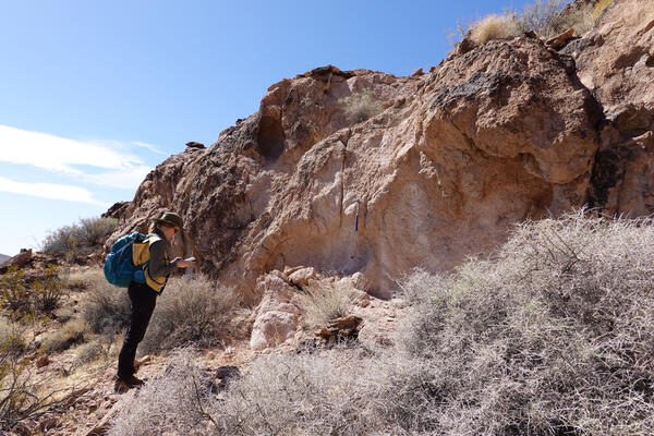Geologist makes notes at an outcrop of volcanic rocks in Death Valley