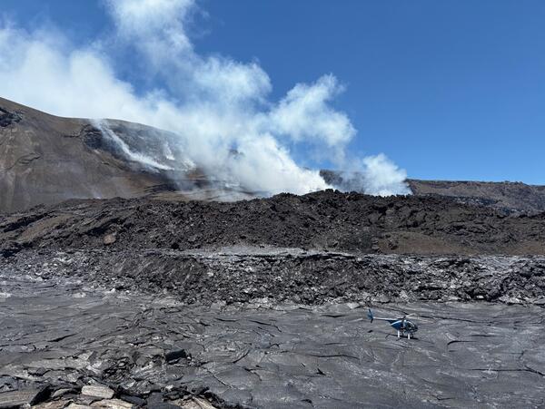 Color photo of black, cooling lava from the August 6th eruption episode 30 with the vents in the background.