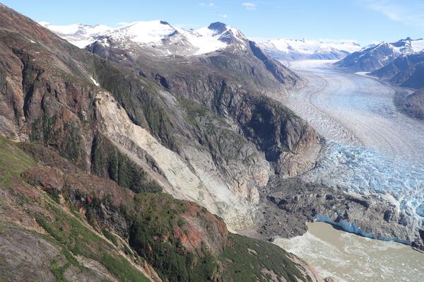 Photo of mountainside with landslide in the center and glacier to the right