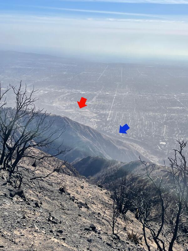 aerial view with burned hillslope in foreground and buildings in image background, arrows pointing to channel