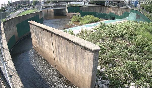A man-made channelized river running along a large dry spillway and dam 