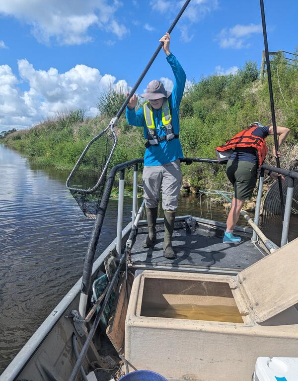 two people stand on a boat holding long nets