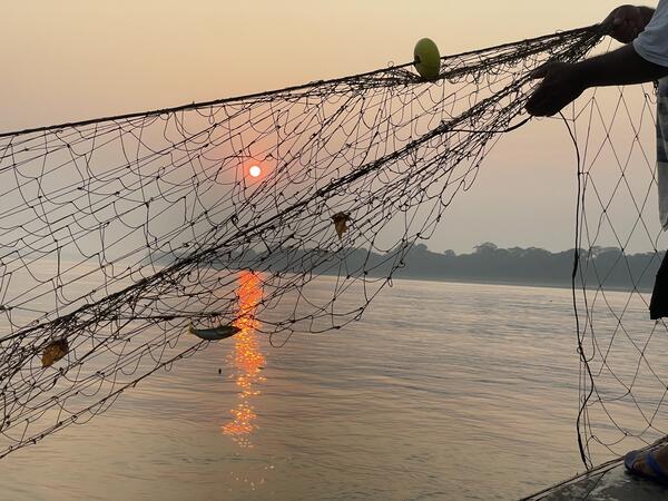 A fisher retrieving a fishing net. 